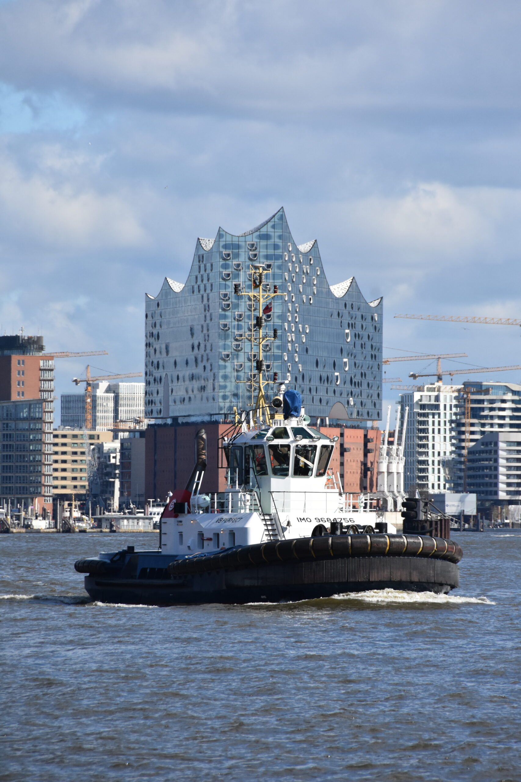 Bild aus dem Hafen Hamburg, im Hintergrund die Hafencity und die Elbphilharmmonie, um Vordergrund ein Hafenschlepper