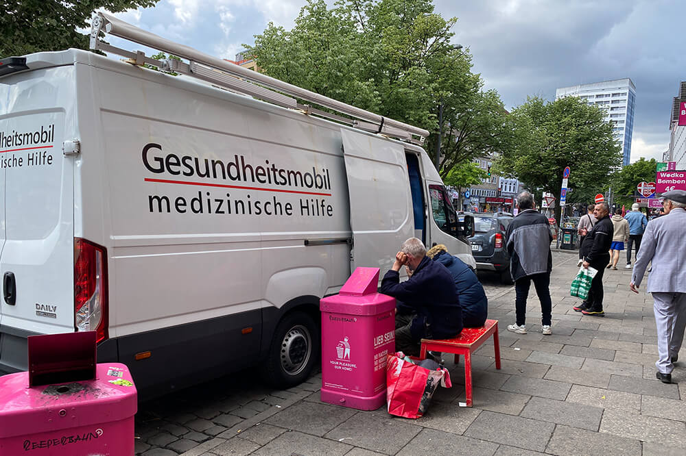 Das Gesundheitsmobil in Hamburg auf der Reeperbahn. Vor dem Mobil warten zwei Patienten