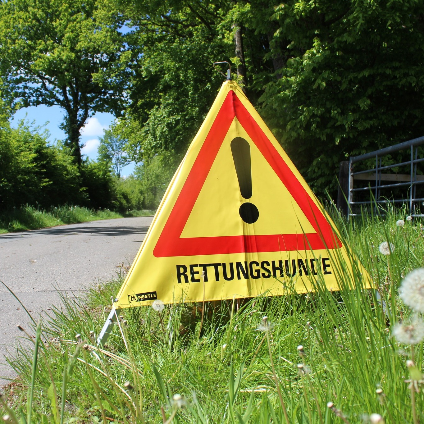 Am Straßenrand ist ein Warndreieck "Rettungshunde" aufgestellt